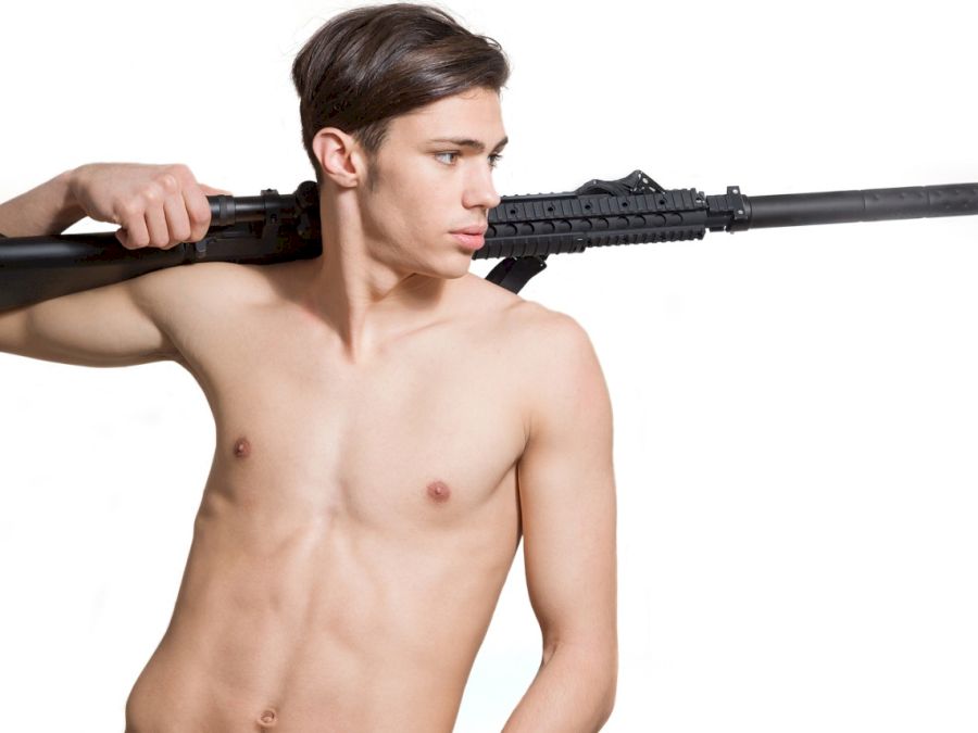 Young semi nude man holding an m16 rifle